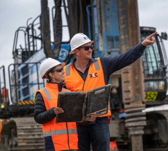 Photo of a man and woman looking at documents and pointing on-site