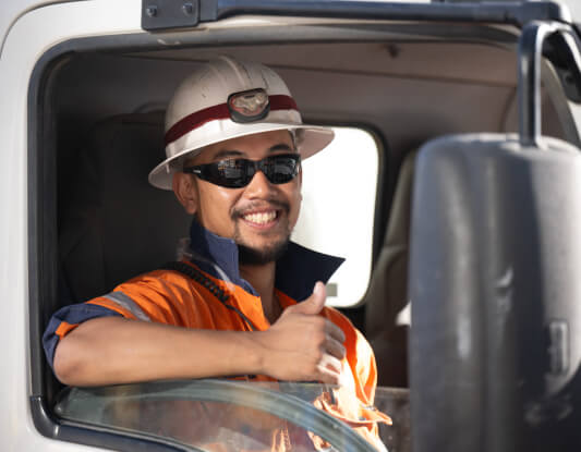 A man in hi-vis sat in a truck, giving a thumbs-up